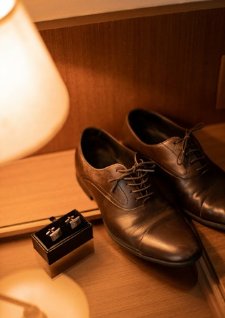 A pair of classic leather dress shoes polished to a shine on a rustic floor.