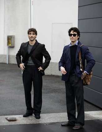 Two men standing next to each other in front of a building