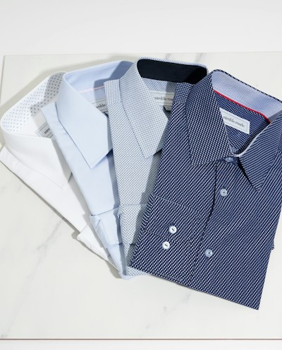 Close-up of soft, breathable cotton dress shirts neatly folded on a wooden table.